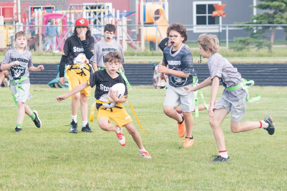 Drake Culp, with the team "Steelers", evades attempts from the team "Raiders" to steal the ball during the inaugural flag football championship at the St. Paul Athletic Park on June 24. Flag football is a gridiron football variant where, instead of tackling, players pull off the flag attached to each other's waist.