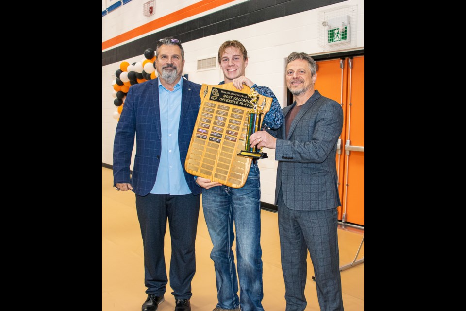 Lions head coach Mark Tichkowsky (left) and coach John Lumby (right) presents the Most Valuable Offensive Player trophy to Zachary Quinton. Quinton is also holding the Most Valuable Offensive Player Award from the Wheatland Football League.