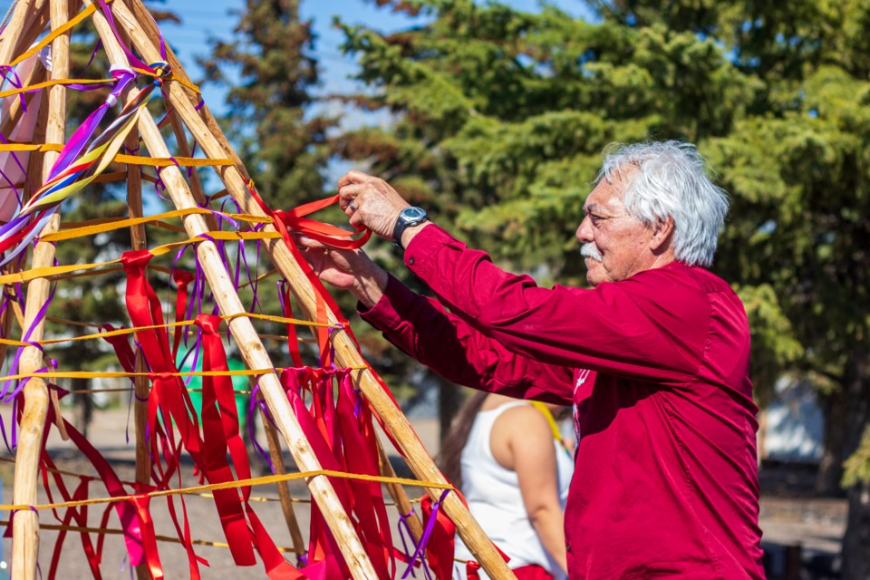 Hinano Rosa, Executive Director at Mannawanis Native Friendship Centre, ties a red ribbon during an event on May 5. 