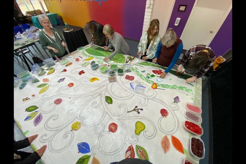 Members of the community collaborate in the creation of the "The Tree of Life" mosaic.
