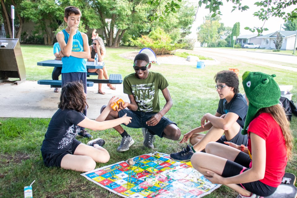Youths play snake and ladder under the shade of a tree from the blazing sun.