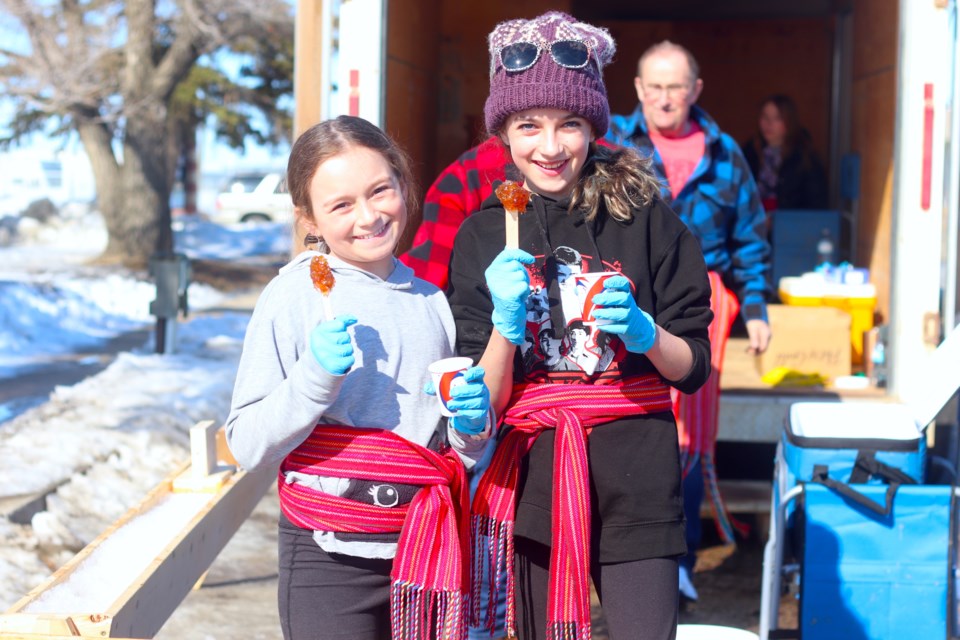 Kaylie Hebert (left) and Sophie Gagne show their maple taffy.