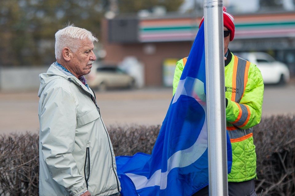 Elder Norman Sinclair (left), a veteran from Cold Lake, raises the Méti flag at Portage College's St. Paul campus on Nov. 16. 
