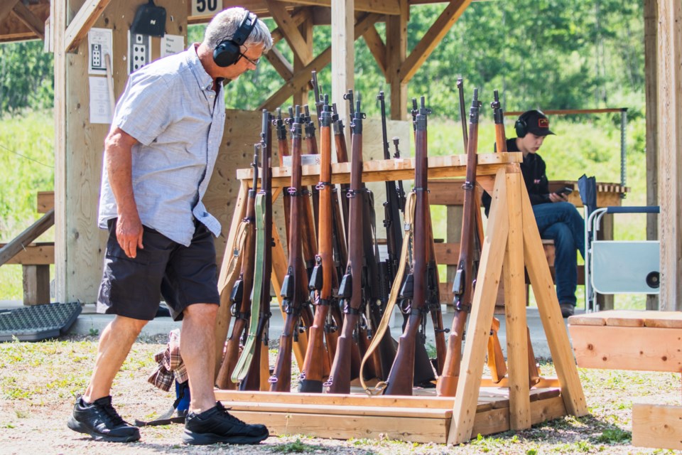 Russell Whitford, coordinator of the tournament, examines the old rifles utilized during the tournament. The rifles in the tournament included both the Lee-Metford and the Lee-Enfield.