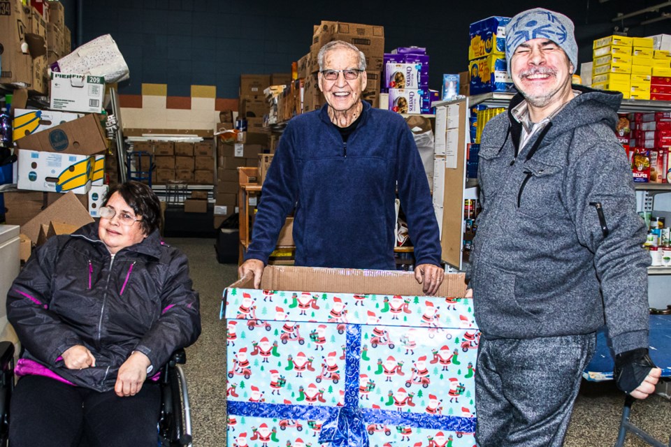Kate Polzin (left) and Lester Hladchuk (right) from SPAN's day program present food donations to the local food bank on Dec. 22. They are joined by  Larry Lambert, board chairman of the food bank.