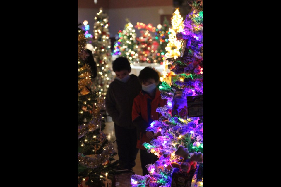 Two young festival goers are silhouetted against the lights of the decorated entries in this year's Festival of Trees