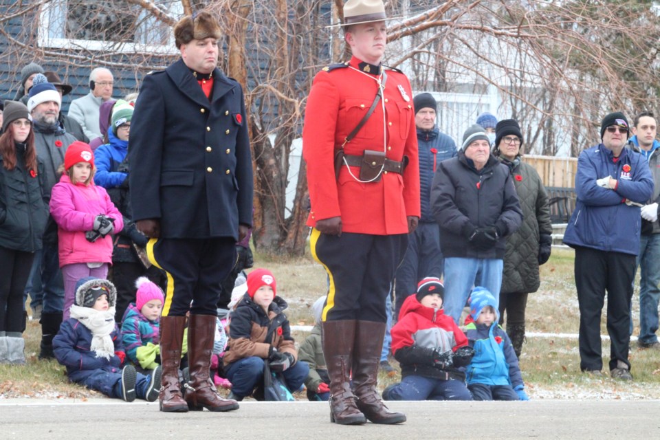 Children watch the Lac La Biche Remembrance Day ceremony from behind members of the parade