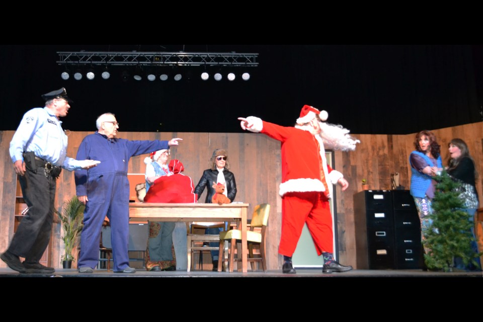 Newspaper staffers Delilah and Sarah show their concern as Sergeant Slattery (Kendall Snyder) is in hot pursuit of J.J. Grimes, but Barney (Lawrence Pidluzny) points out that this is definitely Santa, ready to head out on the toy drop flight.