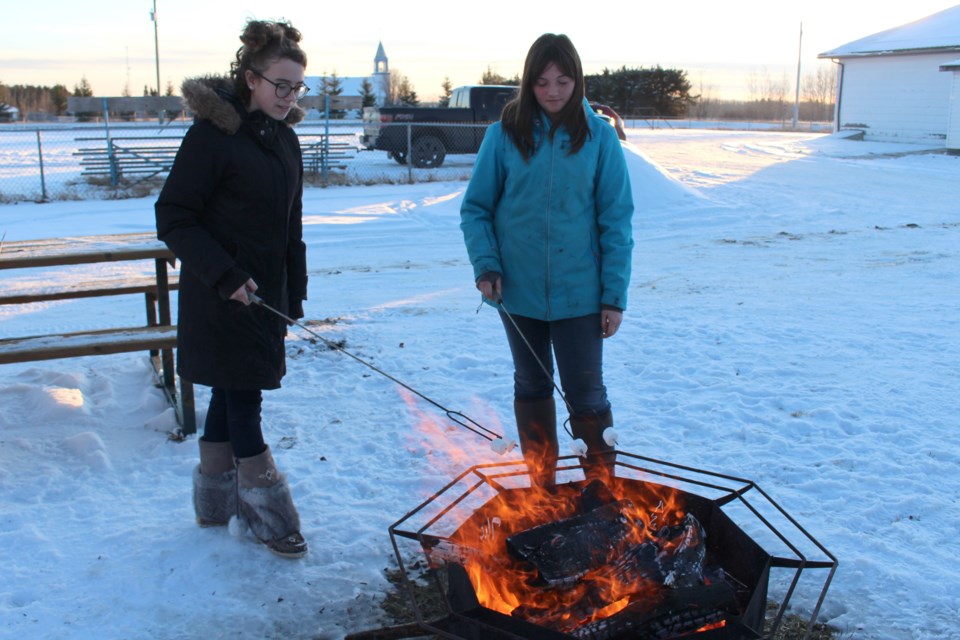 (left to right) Devvyn Kelly, 13, and Brooklyn Graham, 13, roast some marshmallows. Photo by Robynne Henry. 