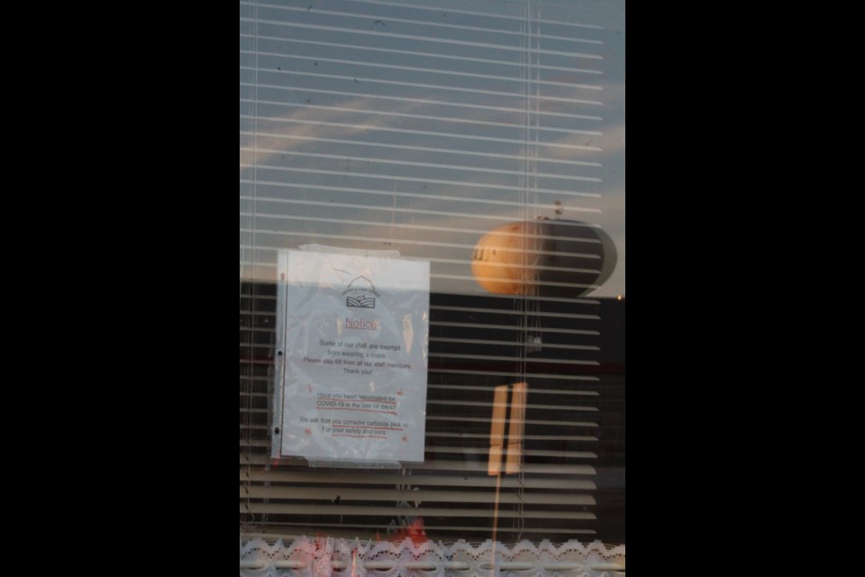 The distinctive Lac La Biche water tower is seen in the reflection of the pet store window displaying a sign based on information that health officials dispute. Staff at the Beaver Hill Road location say it is a policy.