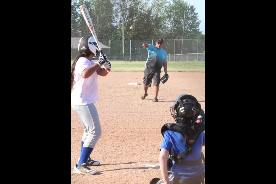 Lac La Biche Minor Ball vice president and U13coach Ryan  Pruden pitches to his daughter as catcher Silas Weening backstops during a practice session on Main 1 last Thursday. 