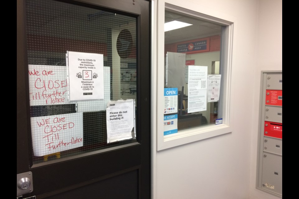 Two hand-written notes on the locked doors of the Lac La Biche Canada Post office on Tuesday.  The doors to the customer service  counter of the community's main postal office are expected to be open again on Wednesday.