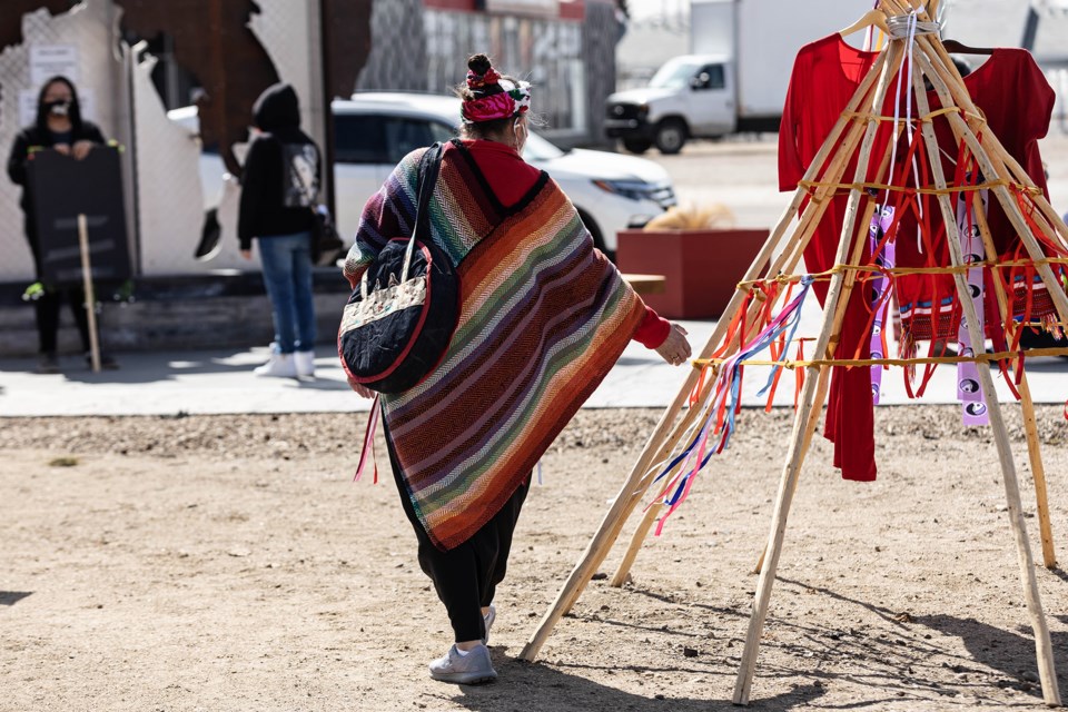 In small groups, those in attendance at an event on Wednesday at the park on main street in St. Paul tied red ribbons to a tipi, in honour of MMIWG.