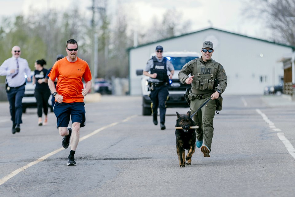 Cpl. Joel Bernadin, a collision reconstructionist, runs alongside Cpl. Andrew Druhan and police dog Lotus, as Lotus carries the team's baton for the final leg of the RCMP Road Race.
