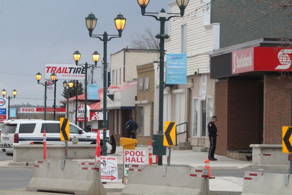 A peace officer speaks to a person outside the Scotiabank on a busy-looking Lac La Biche Main Street.