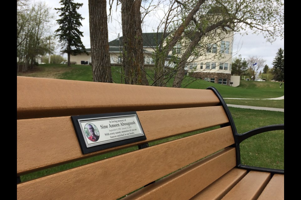 A memorial bench and plaque for Sine Abougoush, a local man who passed away in 2019, sits alongside Lac La Biche lake in McArthur Park.