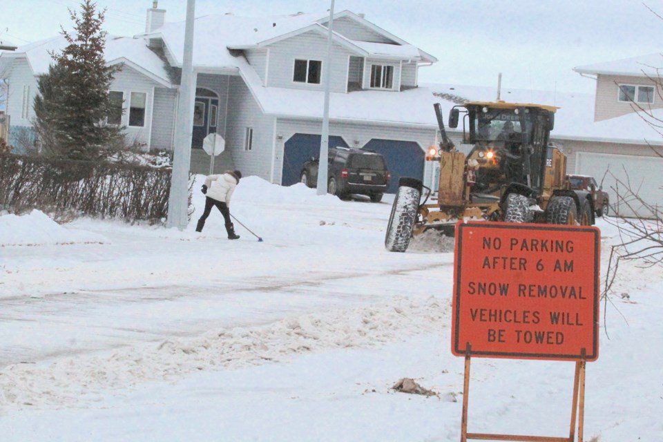 A Lac La Biche County grader takes care of the roadway, while a Dumasfield subdivision resident takes care of the driveway on Wednesday afternoon.