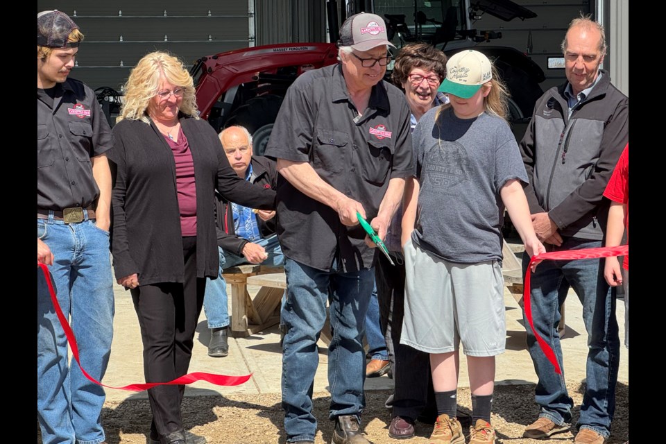 Yvon Caouette cuts the ribbon at the grand opening barbecue for Caouette and Sons Implements newly constructed shop and showroom, hosted April 24.