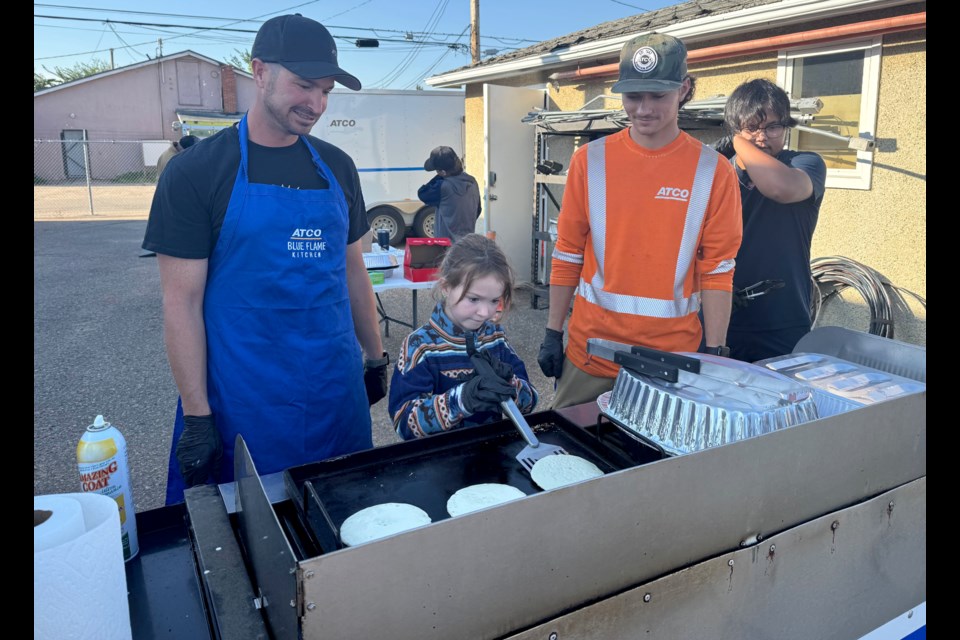Katherine Gales learns how to flip pancakes from her dad, Dan Gales, along with Adam Lacroix, and Selwyn Molina.