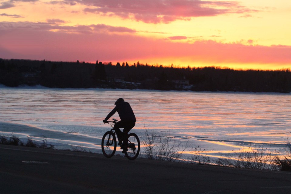 A cyclist rolls along the Lac La Biche lake shoreline recently as the last of the winter ice helps create a colourful sunset backdrop.  Image Rob McKinley