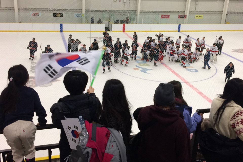 Fans wave the Korean flag at the end of Saturday's game between the Portage College Voyageurs and the Korea University Tigers.