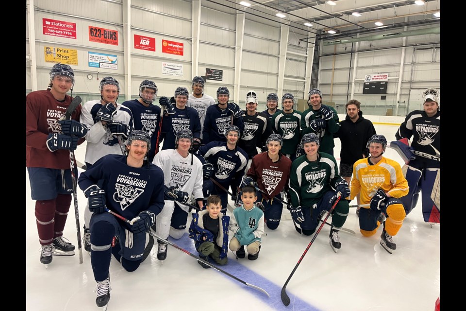 Seven-year old Kanin Cardinal and his younger brother Kaleb in a team photo with the Portage College Voyageurs. Kanin is a big hockey fan and watches every home game. The team invited the brothers for a visit recently.