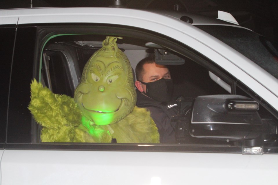 We don't know about a 39-and-a-half-foot pole,  but the Grinch made sure everyone waving at Santa's procession was at least two metres away from a touch.  Mr. Grinch rode with peace officers (here with Enformcement Services Manager Chris Clark) as Santa waved from the back of a peace officer truck through several neighbourhoods on Tuesday night.     Image Rob McKInley.