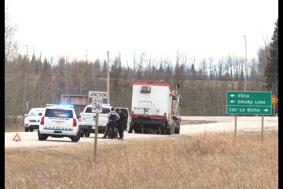 Police officers sit with a truck and trailerlinked to a string of grass fires along Highway 55.