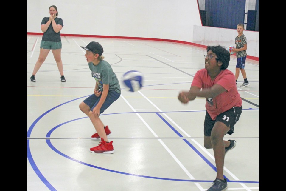 Kolby Hebert and Ishan Chatterjee try to keep pace with the continuous balls that are thrown to them during a serving exercise.