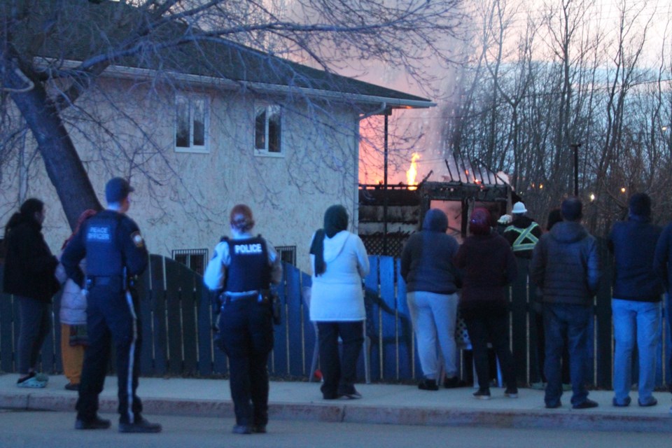 Family, neighbours and others watch as firefighters tackle the flames of a residential garage fire.