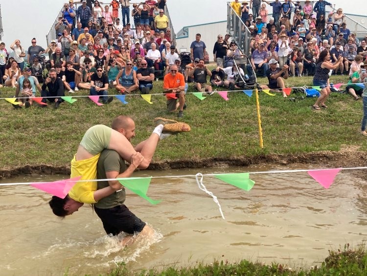 Upside down from Down Under — Lac La Biche Agricultural Society President Aurel Langevin (in orange shirt) watches Chris and Philippa Bowman of Cairns, Australia at last year's wife-carrying race at the Lakeland Country Fair.