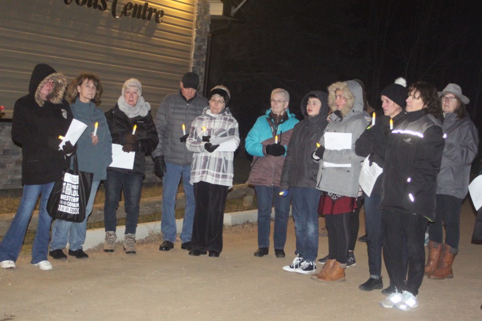 Holding candles and posters of Rose Simonelis, those who attended the vigil on Sunday for the missing Plamondon woman stand outside of the Plamondon Senior Centre. Chris McGarry photo. 