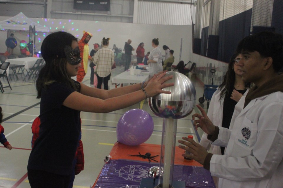 While her hair wasn’t quite staticky enough to stand on end, Kinsley Torraville nonetheless had fun trying out the Van de Graaff Generator that was set up inside the Bold Centre for the Spooktacular Mad Science event, which took place Sunday. Tejasvi Goyal, a member of Mad Science Edmonton, who put on the experiments for the event, show her about the device, which works by static electricity. Chris McGarry photo.