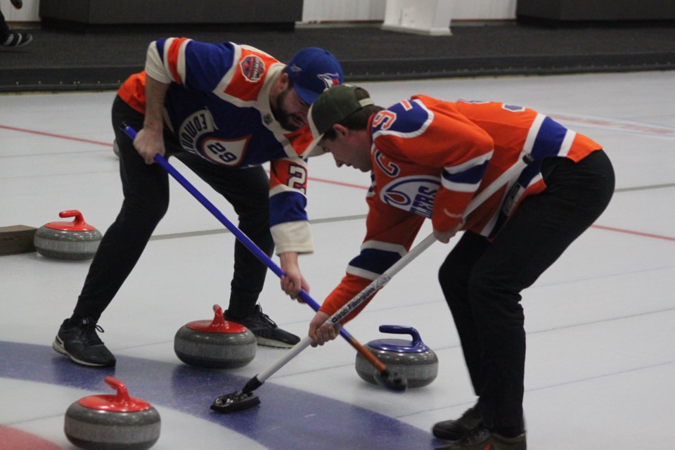 Wade Doucette and Jacob Meyer sweep to their end during a game. Chris McGarry photo. 