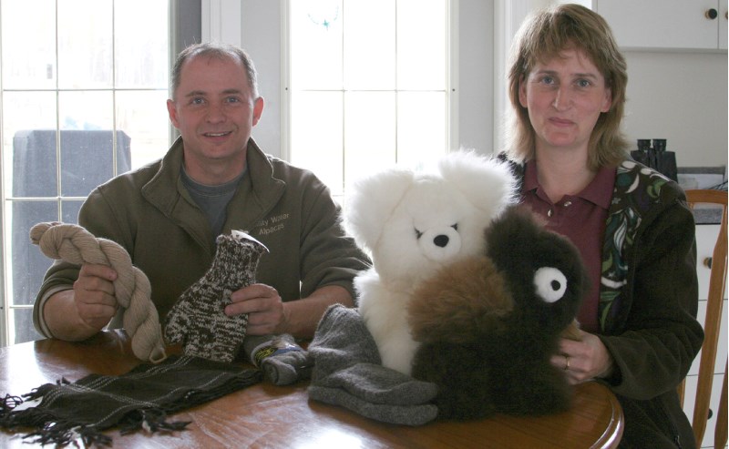 Larry and Therese Scott show the product possibilities of alpaca fibre. The bears are products of Peru while the yarn, mittens, and scarf were processed in Alberta.