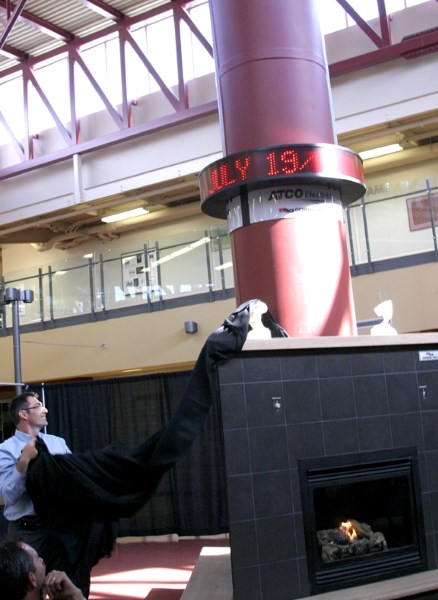 MD CAO Ryan Poole helps unveil the new ATCO clock installed above the GenMec ACL fireplace in the foyer of the Centennial Centre on July 19, while GenMec ACL partner Reginald 