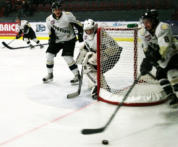 Pontiacs defenceman Donnie Harris yells directions, as forward Devon Kalinski rounds the net with the puck and goalie Connor Creech watches the play develop, during the game