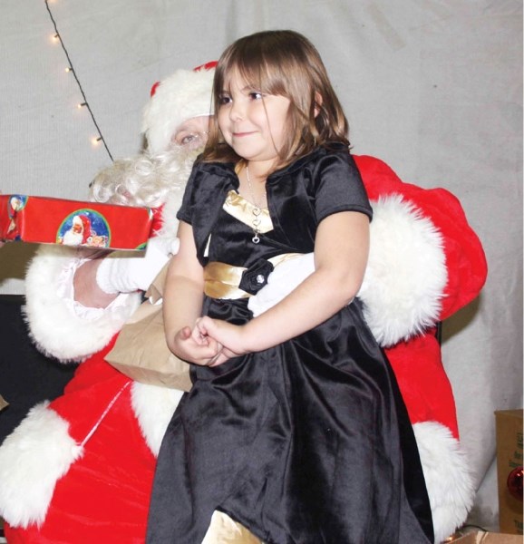 Jordana Kowerchuk sits on Santa&#8217;s knee and accepts a present at the Bonnyville Canadian Native Friendship Centre&#8217;s Christmas dinner Dec. 18.