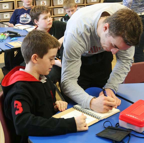 Grade 6 student Zachary Holloway eagerly looks on as Pontiacs forward Marc-Antoine Juneau adds the first signature to Zachary&#8217;s autograph book. Grade 6 students from