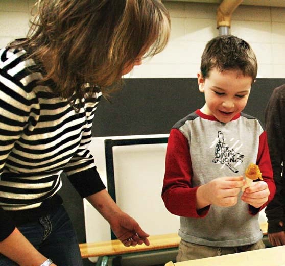 With a little help from parent volunteer Jaime Laturnus, Kindergarten student Brent Hoshowski makes his own maple syrup taffy on a stick at the sugar shack at NDES last