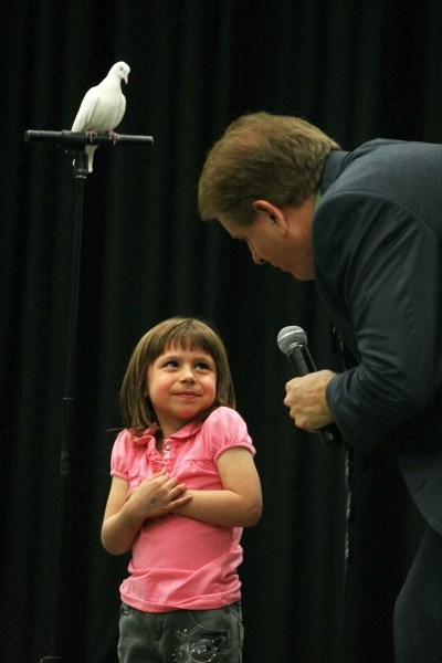 Magician Dana Daniels explains the next trick to a young audience member, while Duane the psychic dove looks on.