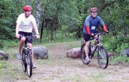 Two competitors cross the finish line of the bike portion of the Moose Adventure Challenge with smiles on their faces. The event took place at the Moose Lake Campground this