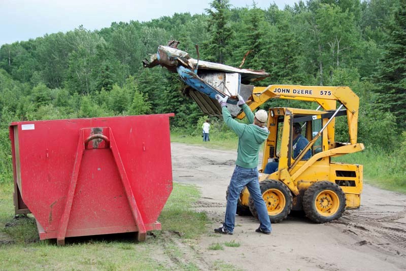 A Cold Lake resident helps a bobcat operator dump a load into a trash bin during the Sandy Beach Cleanup.