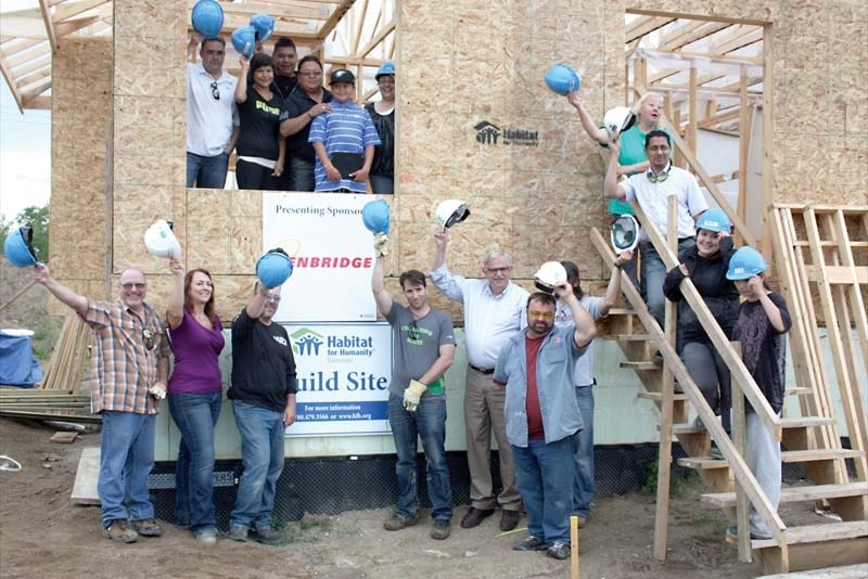 Volunteers raise their hats at the Elizabeth Métis Settlement to celebrate the first-ever Habitat for Humanity project on aboriginal soil.