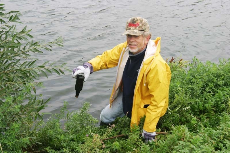 Volunteer Dave Scott empties a bottle pulled from Salwuta Pond, along the shore of Jessie Lake.