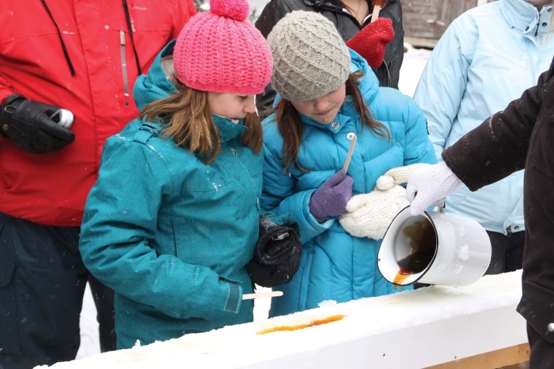 Two girls wait patiently for the maple syrup to hit the snow at the Cabane a Sucre held at Tellier&#8217;s farm for the seventh straight year.
