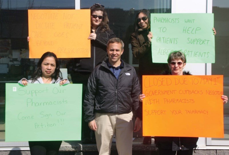 Owner of Value Drug Mart Paul Tellier poses for a picture with a number of employees as they protest the provincial budget by closing the store for two hours last Thursday.