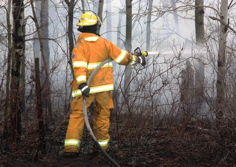 A Bonnyville firefighter extinguishes the final few hot spots at a brush fire last Thursday. The fire burnt just east of Bonnyville, originating in the ditch along Highway 28 