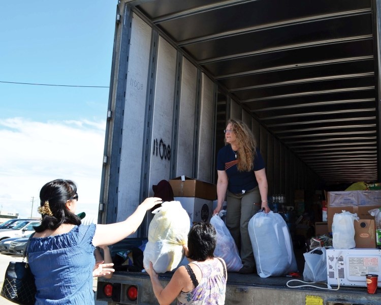 Locals pass bags of donated items to Colette Temblay, who loaded them onto a 50-foot trailer to bring to flood victims in southern Alberta.