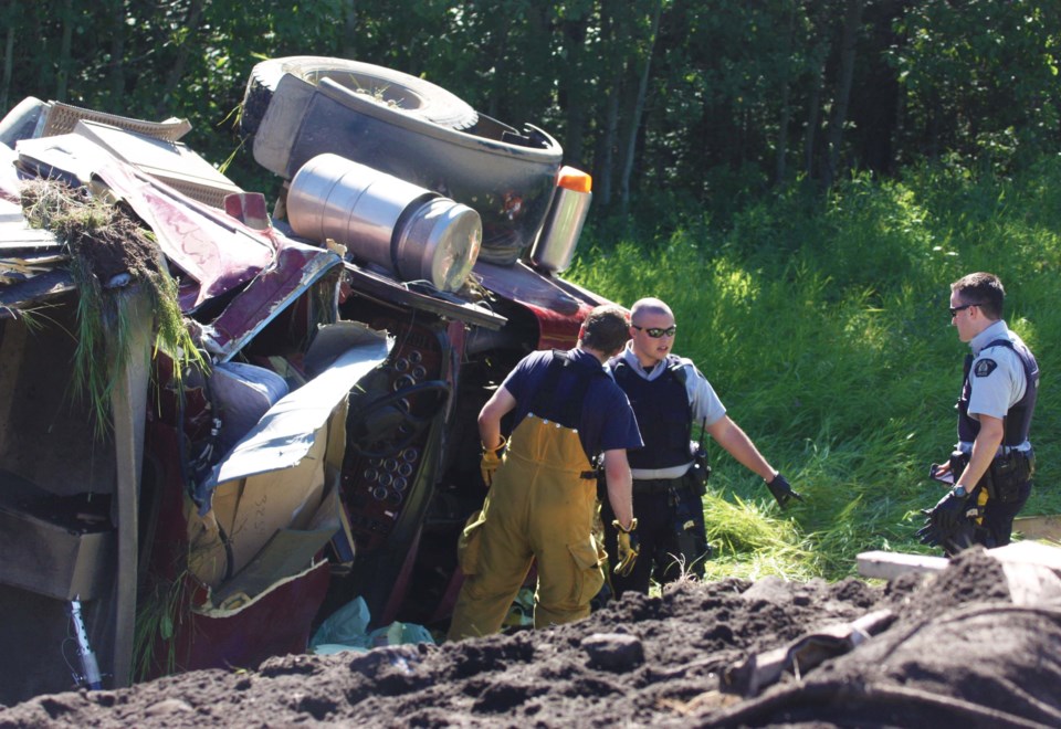 Black dirt is piled up along the edge of the highway, as Bonnyville RCMP and firefighters assess the scene of a North East Bulk Transportation Services truck rollover the